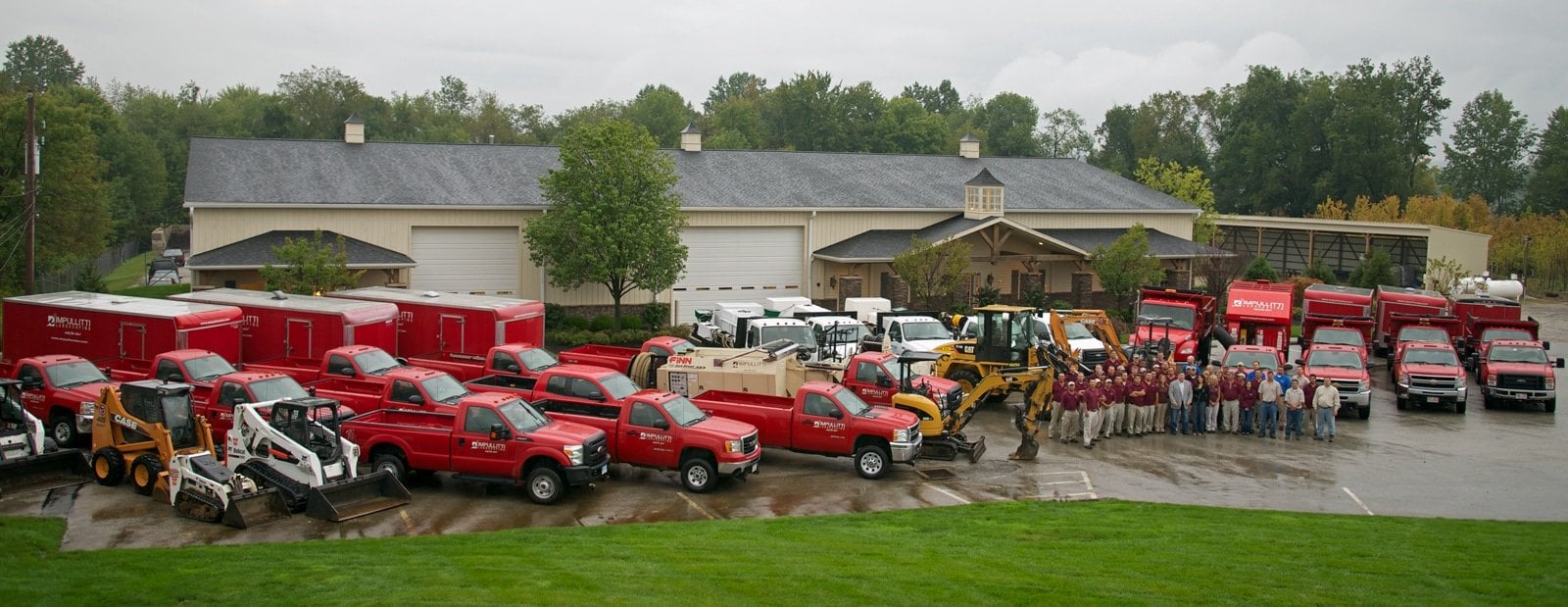 The Impullitti Landscaping team in front of their office with their fleet of vehicles around them